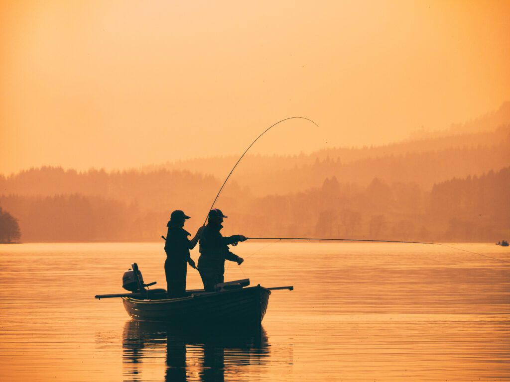 Silhouetten von Fischern auf einem Boot bei Sonnenuntergang